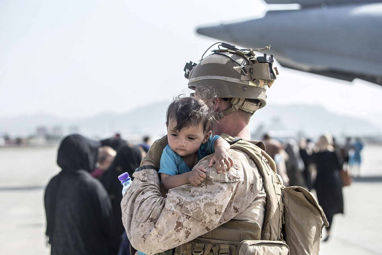 지난 21일(현지시간) 아프가니스탄 카불의 하미드 카르자이 국제공항에서 아프간 대피 작전 중인 미 해병대 병사가 한 아프간 아이를 안아 달래고 있다. 미국 정부는 자국민과 아프간 협력자들의 대피를 지원하기 위해 6000명의 병력을 카불 공항에 파견했으나 공항 인근의 혼란이 이어지고 있어 추가 파병을 검토하는 것으로 알려졌다. 카불=AP