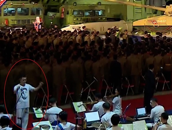 국무위원회연주단 지휘자가 김정은 얼굴이 인쇄된 티셔츠를 입고 있다. 사진=조선중앙TV
