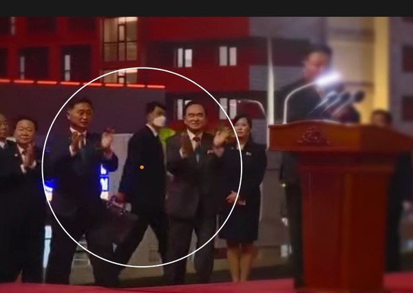 화성지구 1단계 1만세대 준공식에 참석하는 김정은 북한 국무위원장 뒤로 검은 가방을 든 경호원이 지나치고 있다. 사진=조선중앙TV