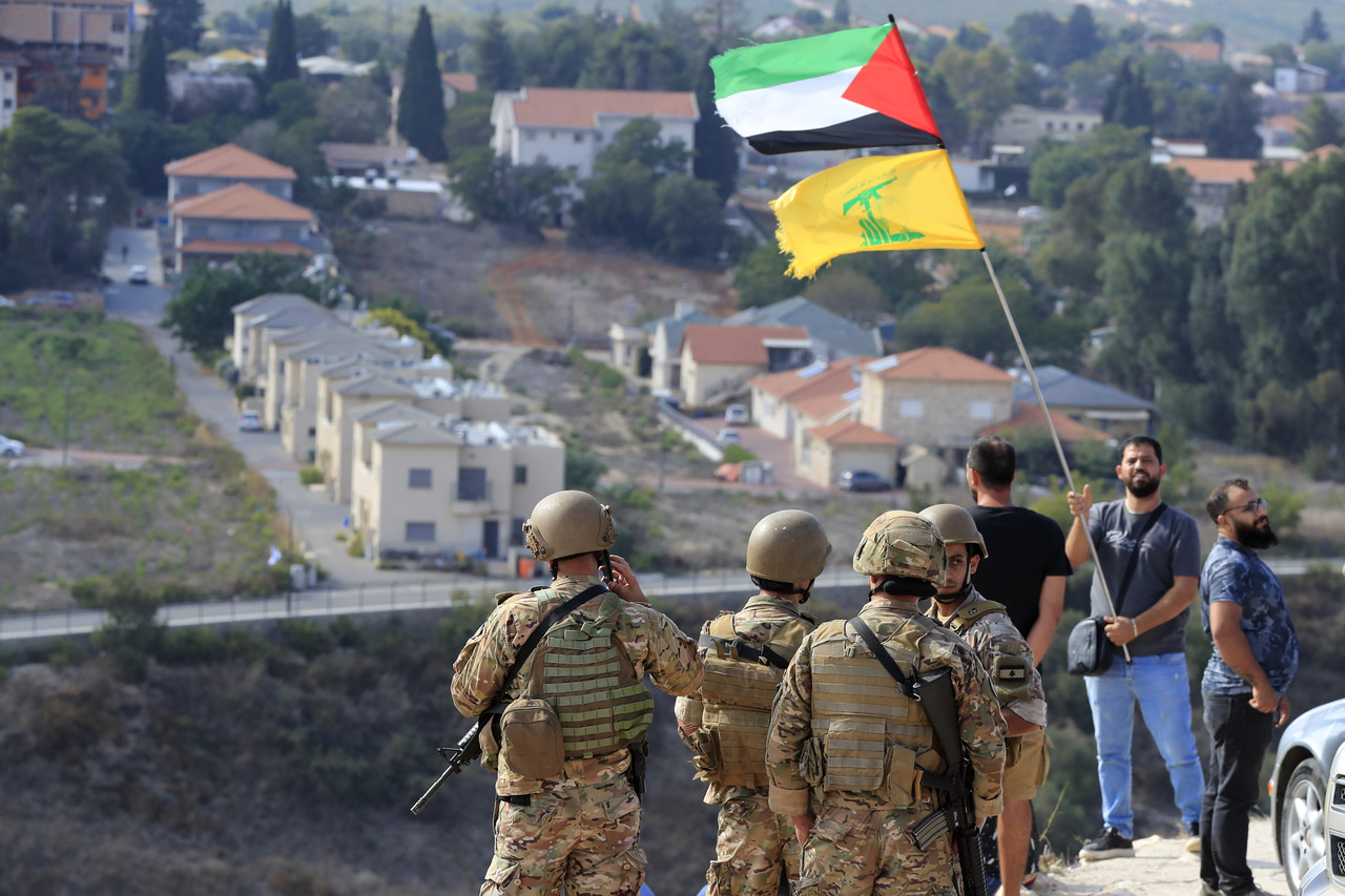 지난 9일(현지시각) 레바논과 이스라엘 국경 마을 크파르 킬라에서 레바논 군인들이 이스라엘 마을이 내려다보이는 언덕에서 대기하는 동안 한 남성이 팔레스타인과 헤즈볼라 깃발을 흔들고 있다. 파르 킬라=AP